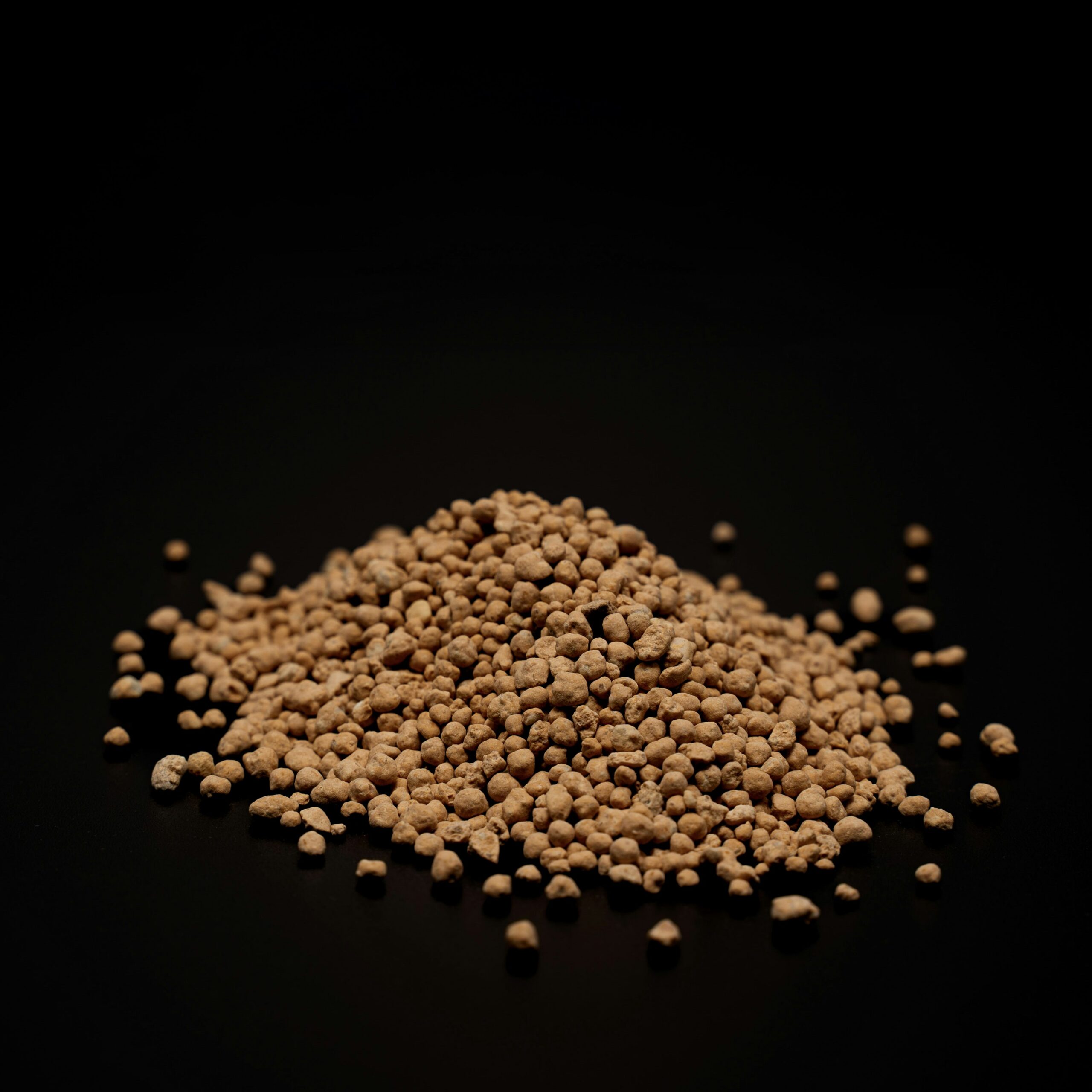 Close-up of light brown granular fertilizer material, illustrative image